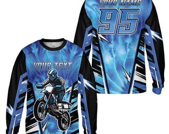 Könnte beinhalten: Langärmeliges Motocross-Trikot mit blauem Batikmuster. Die Vorderseite zeigt einen Fahrer auf einem Dirtbike mit dem Text "YOUR TEXT". Auf der Rückseite stehen "YOUR NAME" und die Nummer "95". Schwarze und blaue Akzente runden das Design ab.