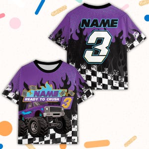 May include: Purple and black short-sleeve shirt with a monster truck graphic. The shirt features the text "NAME" and the number "3" in white and blue. The design includes flames and a checkered flag pattern.
