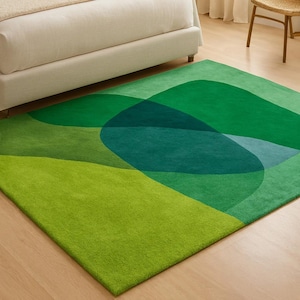 May include: A green rug with an abstract design. The rug features overlapping shapes in various shades of green and teal. The rug is rectangular and has a soft, plush texture, suitable for a living room or bedroom.