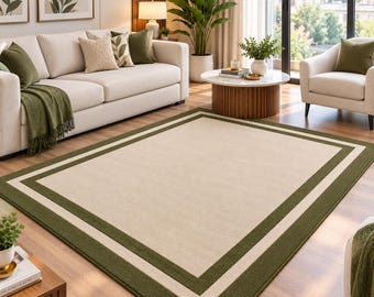 Pode incluir: Um tapete retangular com um grande painel central bege sólido, emoldurado por uma borda larga verde-oliva escura e uma borda interna fina de cor creme. O tapete possui uma textura plana e uniforme com bordas retas e bem definidas.