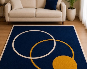 Pode incluir: Um tapete retangular com um fundo azul-marinho profundo e um padrão geométrico de dois círculos sobrepostos em creme e amarelo-mostarda, finalizado com uma borda sólida em creme que emoldura toda a peça em todos os lados.