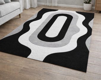 Pode incluir: Um tapete retangular com um design moderno. O tapete apresenta um esquema de cores preto, branco e cinza com um padrão abstrato e ondulado. O tapete é colocado sobre um piso de madeira.