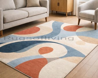 Pode incluir: Um tapete retangular com um design abstrato. O tapete apresenta um fundo creme com grandes formas sobrepostas em tons de azul, laranja e bege. O texto "Rugsofliving" é visível no tapete.