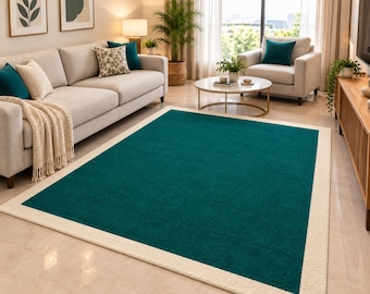 Pode incluir: Um tapete retangular com um painel central sólido em verde-azulado profundo, emoldurado por uma borda larga e texturizada em branco sujo. O tapete possui uma superfície de pelo curto e está posicionado sobre um piso claro e nivelado.