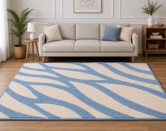 Pode incluir: Um tapete retangular com uma base de cor creme e um padrão repetitivo de linhas onduladas grossas e texturizadas em azul claro que atravessam a superfície. O tapete tem uma construção de pelo curto com bordas acabadas em tom azul.