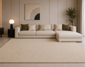 Pode incluir: Uma sala de estar moderna com um grande sofá de canto bege e almofadas em tons neutros e verde oliva. Um grande tapete bege cobre o chão. Uma pintura com cores neutras está pendurada na parede.