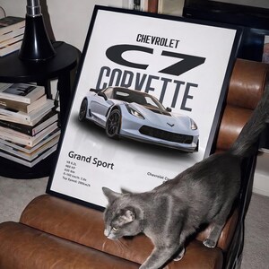May include: A framed poster featuring a light blue Chevrolet C7 Corvette Grand Sport. The poster includes technical specifications and the Chevrolet logo. A gray cat walks across a brown leather chair in front of the poster.
