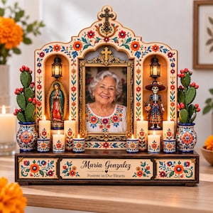 May include: A wooden memorial altar featuring a central framed photograph of an older person, flanked by two small lanterns, two potted cactus plants, and several lit candles. The base displays the text Maria Gonzalez and Forever in Our Hearts.