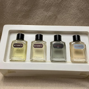 May include: A set of four Aramis fragrance bottles in a white tray. The bottles have black caps and labels with the Aramis brand name. The set includes Eau de Toilette and After Shave.
