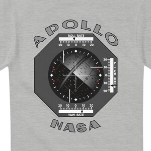 May include: A light grey t-shirt with a graphic of an Apollo spacecraft instrument panel. The design includes the words "APOLLO" and "NASA", along with gauges for roll, pitch, and yaw rate.