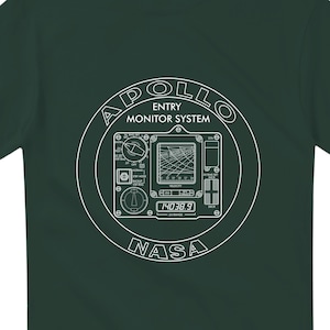 May include: Dark green t-shirt with a white graphic depicting the Apollo Entry Monitor System. The design includes the text "APOLLO ENTRY MONITOR SYSTEM" and "NASA", along with a detailed diagram of the system's components.