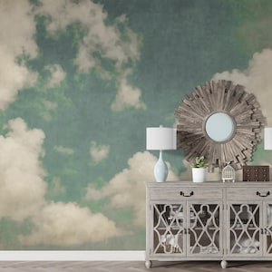 May include: A decorative wall mural featuring a cloudy sky design in shades of blue, green, and cream. A gray cabinet with lamps, a mirror, and decor is in front of the mural. The cabinet has glass doors.