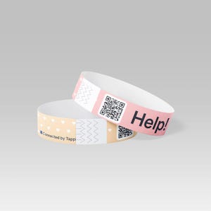 Könnte beinhalten: Zwei weiße Papierarmbänder. Eines ist hellrosa mit einem QR-Code und dem Wort "Help!" in Schwarz. Das andere ist hellpfirsichfarben mit kleinen weißen Herzen und dem Text "Connected by Tappi". Beide haben ein Zickzackmuster.