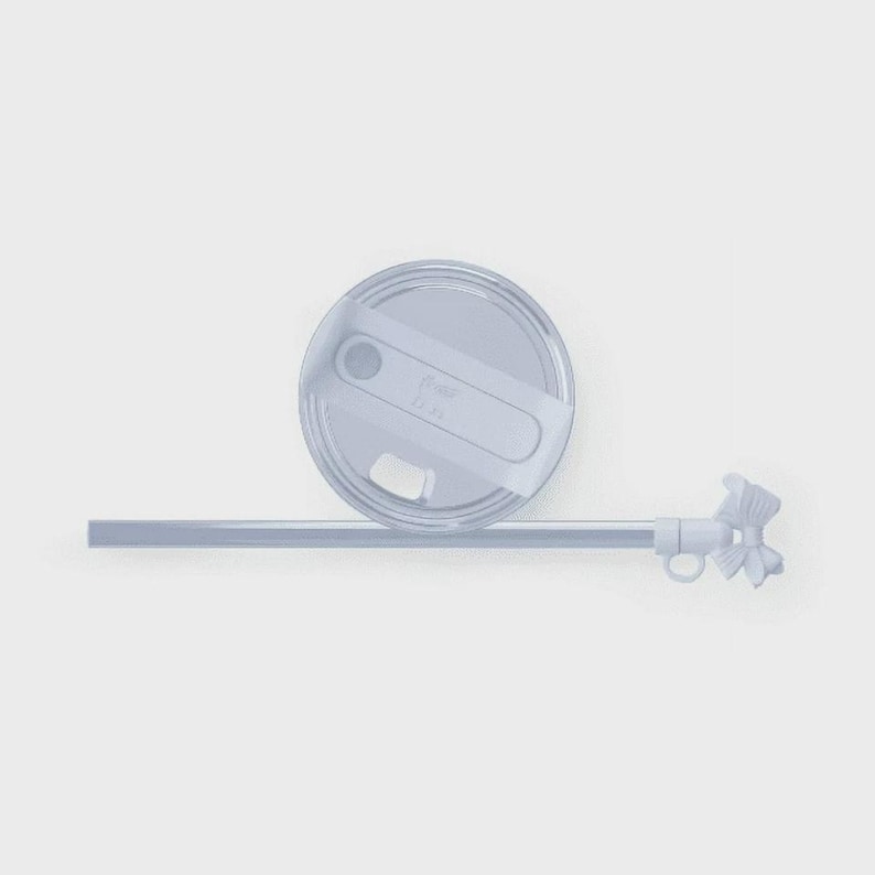 May include: A pale blue tumbler lid with a white slider and a matching straw. The straw has a decorative bow at the end. The lid is round and has a small opening for the straw. The background is a solid light grey.