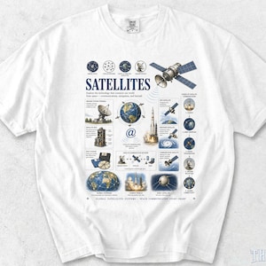 May include: A white t-shirt featuring a detailed educational graphic titled SATELLITES. The print includes illustrations of space technology, a rocket launch, Earth, and various satellite communication systems with descriptive text labels.