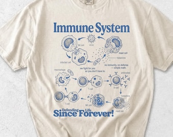 Könnte beinhalten: Ein elfenbeinfarbenes Kurzarm-T-Shirt mit einem blauen Grafikdruck des Immunsystems. Das Design enthält Illustrationen biologischer Zellen, Beschriftungen sowie den Text Immune System und Defending Life Since Forever! auf der Vorderseite.
