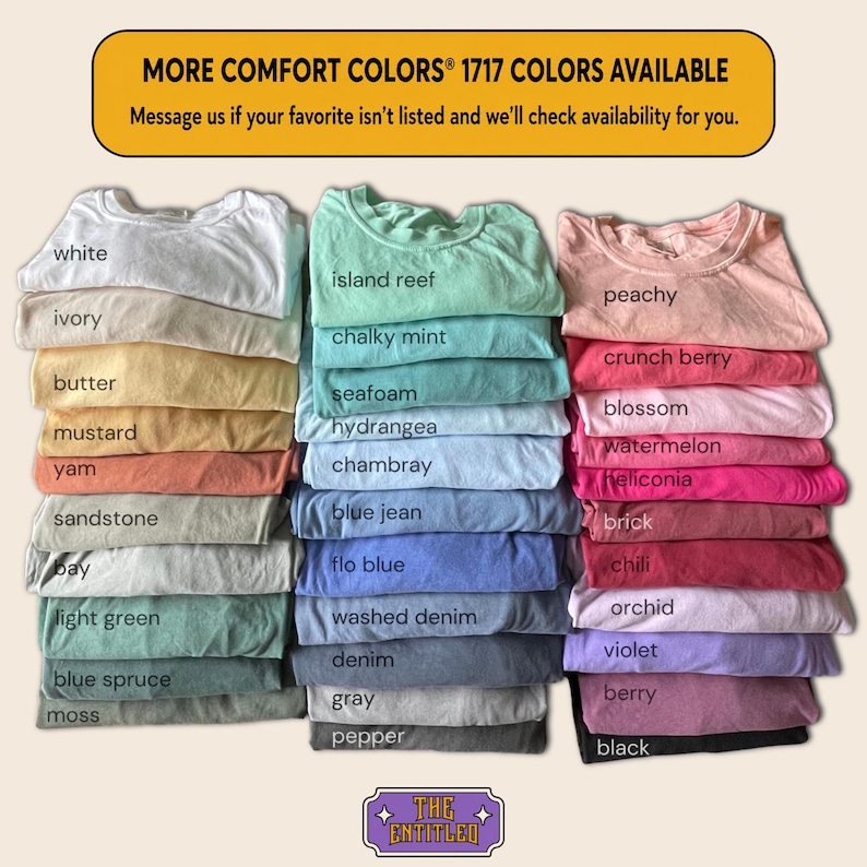 May include: A collection of folded Comfort Colors 1717 t-shirts arranged in three vertical stacks. The shirts display a wide variety of colors, each labeled with text including white, ivory, butter, mustard, yam, sandstone, bay, light green, blue spruce, moss, island reef, chalky mint, seafoam, hydrangea, chambray, blue jean, flo blue, washed denim, denim, gray, pepper, peachy, crunch berry, blossom, watermelon, heliconia, brick, chili, orchid, violet, berry, and black.