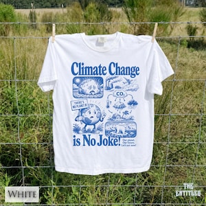 May include: A white short-sleeve t-shirt featuring a blue graphic print with the text Climate Change is No Joke! The design includes illustrations of a sweating earth, a sign reading THERE'S NO PLANET B!, CO2 emissions, and a polar bear.