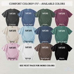 以下が含まれることがあります： さまざまな色のComfort Colors 1717 Tシャツのコレクション。各シャツには「PLANT LOVER」の文字がプリントされています。色はペッパー、ブルージーンズ、モス、ベリー、アイボリー、シャンブレー、デニム、ライトグリーン、ブロッサム、ホワイト、エスプレッソ、ブラックです。