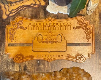 May include: Wooden Ouija board with a planchette, alphabet, numbers, and the words "Carnivalias Spirit Converser".