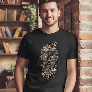 Könnte beinhalten: Schwarzes T-Shirt mit einer detaillierten Illustration eines aus Büchern geformten Gesichts, komplett mit Brille und Bart. Das Design verwendet warme Farben und komplizierte Details. Die Person trägt das T-Shirt. Der Hintergrund zeigt eine Backsteinmauer und Bücherregale.