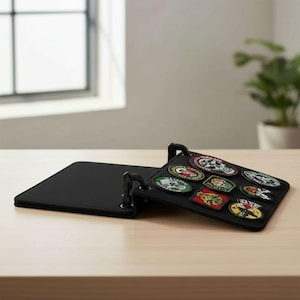 May include: Black patch holder with several embroidered patches in various colours. The patches display different designs, including skulls and logos. The holder is open, showing the patches on a black surface.