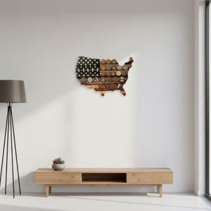 May include: A wooden wall hanging in the shape of the United States, with a design that incorporates the American flag and a collection of coins. The flag portion features stars and stripes, while the rest is filled with various coins.