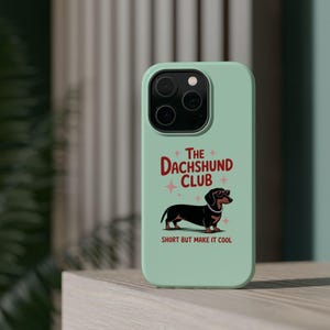 Puede incluir: Funda de teléfono verde menta con un perro salchicha de dibujos animados con gafas y un collar de perlas. El texto "THE DACHSHUND CLUB" está encima del perro, con "SHORT BUT MAKE IT COOL" debajo.