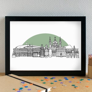 May include: A black and white line drawing of the Madrid skyline, featuring the Royal Palace, the Almudena Cathedral, and the Plaza Mayor. The skyline is set against a green background.