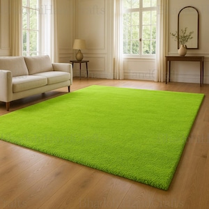 Peut inclure: Un grand tapis rectangulaire vert vif est au centre d'une pièce à vivre. Le tapis, à l'aspect moelleux et texturé, recouvre une grande partie du sol en bois. La pièce comprend un canapé crème, des fenêtres et des éléments décoratifs.