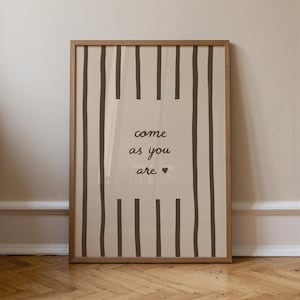 May include: A framed print with a light brown wooden frame. The print features vertical dark brown stripes on a cream background. The words "come as you are" are written in a handwritten font, with a small heart symbol.
