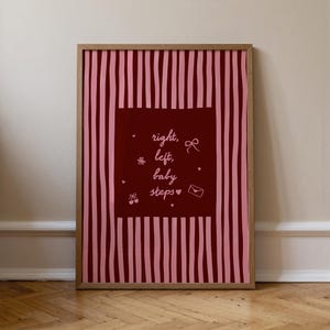 Puede incluir: Un estampado enmarcado con un fondo burdeos y rayas rosas verticales. Un cuadrado burdeos en el centro presenta las palabras "right, left, baby steps" en escritura blanca, junto con pequeñas ilustraciones de un lazo, una flor, cerezas y un sobre.