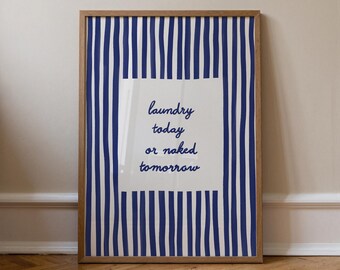 May include: A framed print with a wooden frame. The artwork features a white rectangle with the text "laundry today or naked tomorrow" in a handwritten font. The background has vertical blue and white stripes.