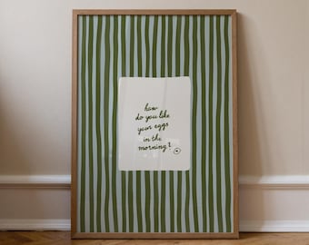 May include: A framed print with a green and white striped background. A white rectangle in the center features the text "how do you like your eggs in the morning?" in a handwritten style. The frame is made of wood.