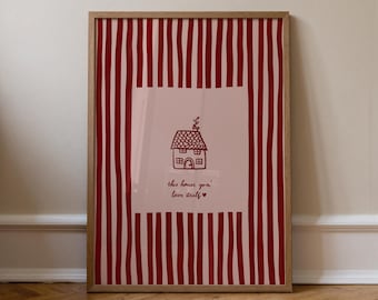 May include: A framed art print featuring a red and white striped background. The center has a light pink square with a line drawing of a house and the text "this house gon' love itself" in black script.