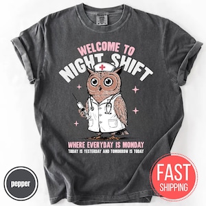 May include: Dark gray t-shirt with a graphic of an owl dressed as a nurse, holding a syringe. Text reads "WELCOME TO NIGHT SHIFT" and "WHERE EVERYDAY IS MONDAY TODAY IS YESTERDAY AND TOMORROW IS TODAY".