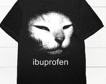May include: Black t-shirt featuring a white, stylized cat face with closed eyes. The word "ibuprofen" is printed in white below the cat image. The shirt has a crew neck and short sleeves.