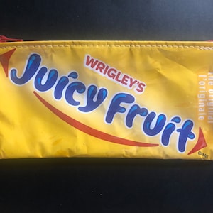May include: Yellow pencil case with a red zip, featuring the "Juicy Fruit" logo in blue. The pencil case is made from a repurposed Wrigley's Juicy Fruit gum wrapper.