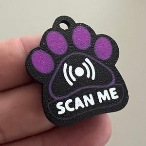 Könnte beinhalten: Schwarzer Pfoten-Anhänger mit lila Pfotenballen und einem weißen Signal-Symbol. Der Anhänger trägt den weißen Schriftzug "SCAN ME". Ein lila Banner mit "NFC" und einem Smartphone-Symbol befindet sich oben rechts.