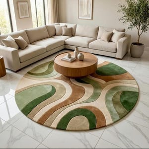 May include: A modern living room featuring a large beige sectional sofa, a round wooden coffee table, and a colorful circular rug. The rug has a wavy pattern in shades of green, brown, and beige. A small potted olive tree adds a touch of nature.