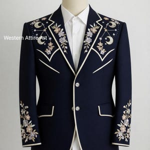 May include: Navy blue blazer with floral and celestial embroidery. The blazer features white trim and two buttons. The sleeves and shoulders are adorned with embroidered flowers, moons, and stars. The text "Western Attire Art" is visible on the left side.