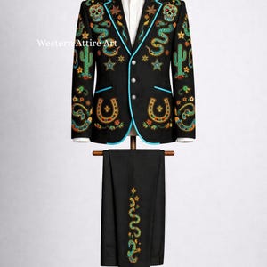Könnte beinhalten: Schwarzer Anzug mit farbenfrohen Stickereien. Die Jacke hat türkisfarbene Paspeln, Totenköpfe, Kakteen, Sterne und Hufeisen-Designs. Die passende Hose hat ein Schlangenmuster. Der Anzug wird auf einer Schaufensterpuppe präsentiert.