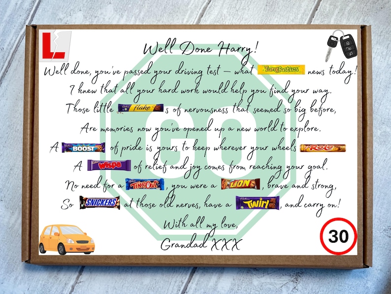 May include: A rectangular cardboard gift box featuring a printed congratulatory message for a driving test pass. The design includes a red L-plate, car keys, a yellow car, a speed limit sign, and various candy bars integrated into the text.
