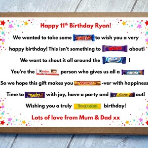 May include: A rectangular brown cardboard gift box featuring a white insert with colorful star confetti borders. The text reads Happy 11th Birthday Ryan! followed by a birthday message incorporating various candy bar brand names as puns.