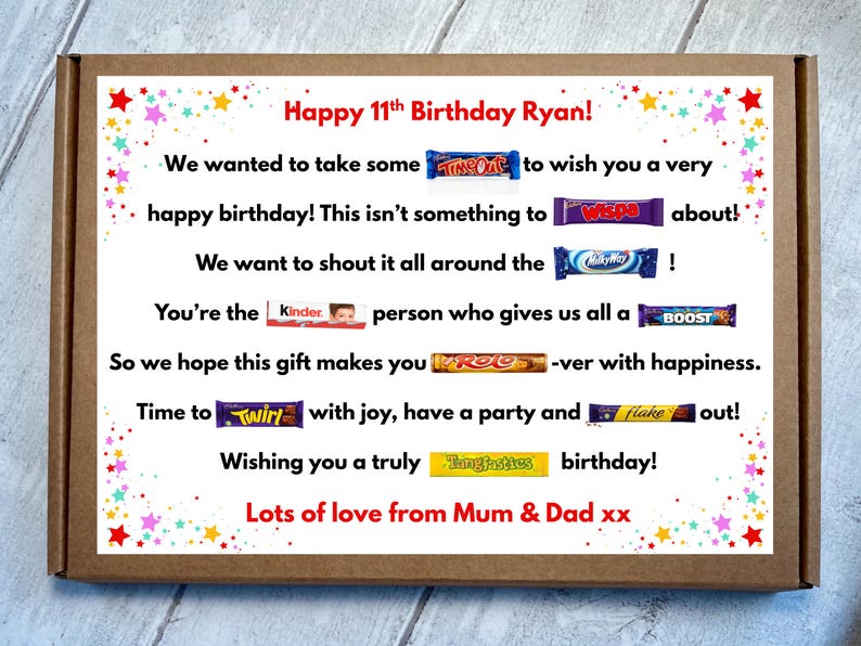 May include: A rectangular brown cardboard gift box featuring a white insert with colorful star confetti borders. The text reads Happy 11th Birthday Ryan! followed by a birthday message incorporating various candy bar brand names as puns.