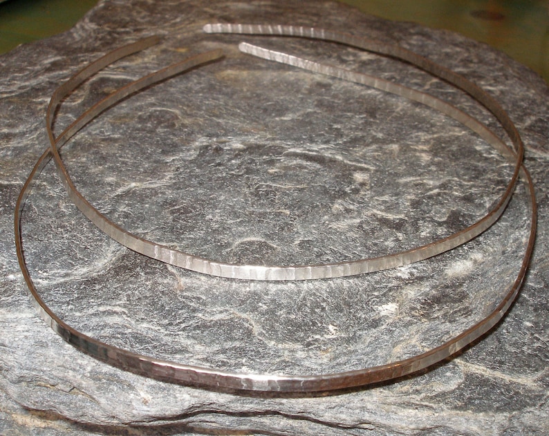 A round or oval shaped sterling silver 925 headband.  Measuring 12 cm wid3 normally, it has a heavily textured surface and is highly polished.