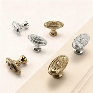 Puede incluir: Una variedad de tiradores decorativos para armarios en acabados dorados y plateados. Los tiradores tienen forma ovalada con detalles florales ornamentados y una base elevada. Para muebles y decoración del hogar.