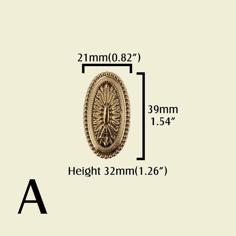 May include: A gold-colored, oval-shaped furniture knob with a detailed floral design. The knob measures 39mm (1.54 inches) in height and 21mm (0.82 inches) in width. The height is 32mm (1.26 inches). The letter "A" is in the lower left corner.