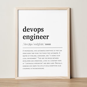 May include: A framed print with the words "devops engineer" in a bold, black font. Below, the phonetic pronunciation and the word "noun" are displayed. The definition of a devops engineer is also included in the print.