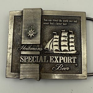 May include: A rectangular silver-toned metal belt buckle. The buckle features the text "Heileman's SPECIAL EXPORT Beer" and a sailing ship. The top of the buckle has the text "You can travel the world over and never find a better beer."